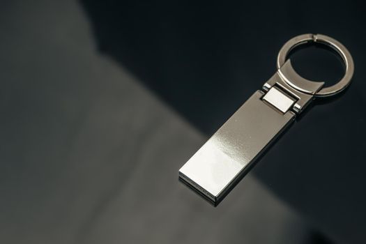 Stylish masculine metal key charm on black glass background
