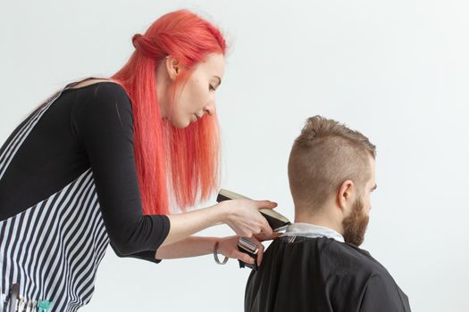 Hairdresser, hairstylist and barber shop concept - woman hairstylist cutting a bearded man