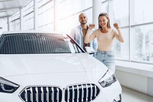 Young happy couple choosing a car in car dealership