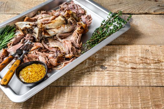 Roast pork knuckle eisbein meat on a baking pan with herbs. Wooden background. Top view. Copy space