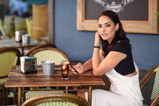 Girl with blue eyes sitting on urban cafe using smart phone