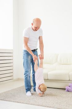 Fatherhood and family concept - Father and small toddler baby indoors at home, playing.