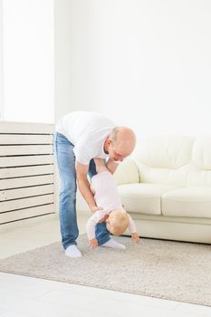 family, parenthood and fatherhood concept - happy father playing with little baby girl at home