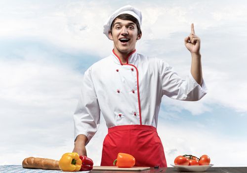 Young male chef standing near cooking table
