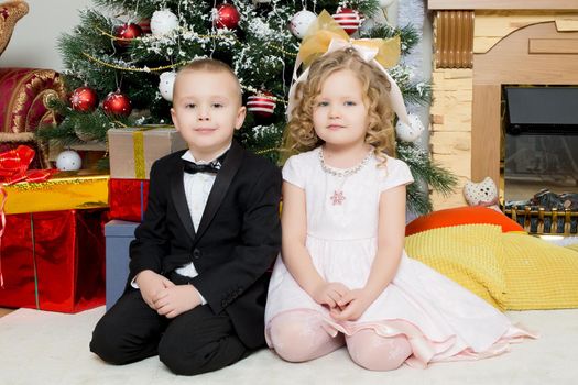 Boy and girl with gifts near the Christmas tree.