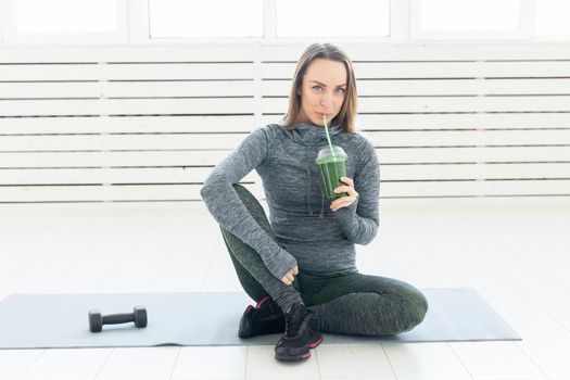 Healthy lifestyle, people and sport concept - Woman with healthy juice drinking for sport and fitness on white background.