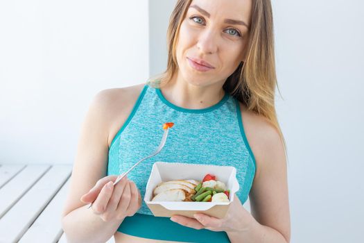 Healthy, fitness and people concept - Close up of dietary salad and woman in sports wear