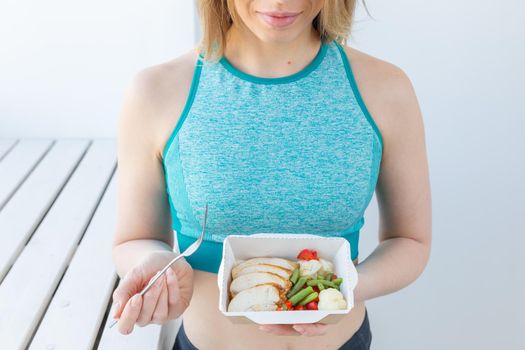 Healthy, fitness and people concept - Close up of dietary salad and woman in sports wear