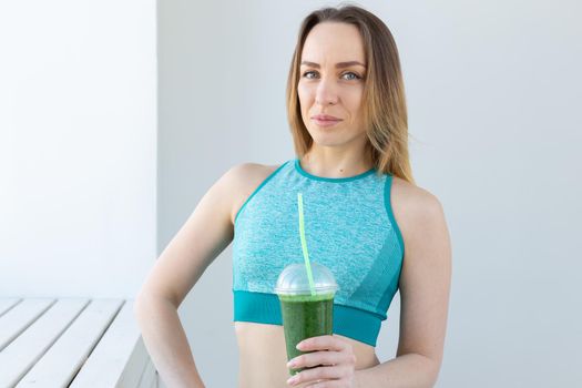 Healthy, sport, diet and people concept - Successful fitness urban woman recommending detox smoothie