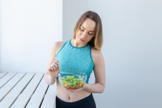Healthy lifestyle, fitness and diet concept - dietary salad and woman in sports wear