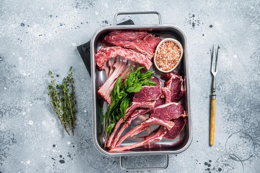 Uncooked Raw lamb, mutton chops in a steel kitchen tray. Gray background. Top view