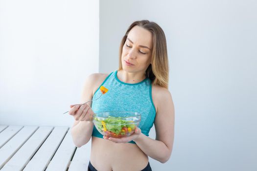 Healthy lifestyle, fitness and diet concept - dietary salad and woman in sports wear