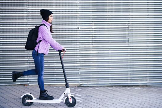 Young woman in her twenties riding an electric scooter.