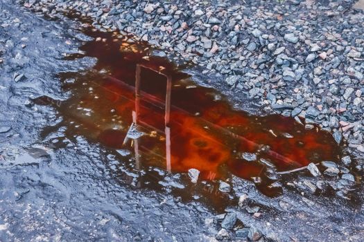 Puddle of red potash chemical fertilizer after rain on a crushed stones of agriculture industrial plant