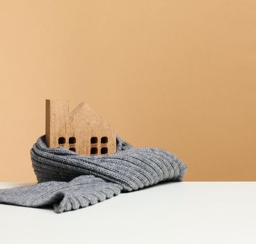 wooden miniature house wrapped in a gray knitted scarf. Building insulation concept, loans for repairs