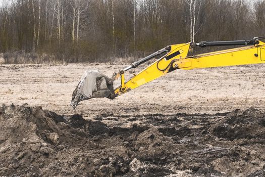 Excavator bucket digging a trench in the ground at a construction site. Excavation industrial work with land and soil