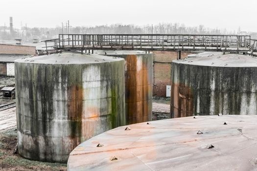 Old fuel oil tanks with fuel oil stains and traces of rust at an abandoned industrial plant
