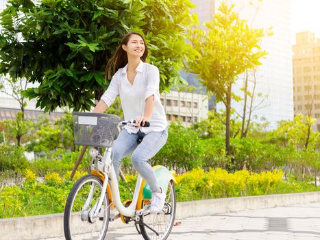 Young attractive woman riding  bicycle in the city park