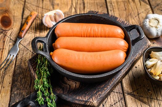 Sausages bratwurst from pork meat in a pan. wooden background. top view