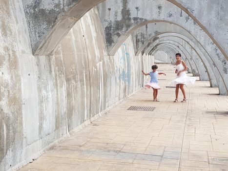 Mother and daughter dancing under the arches of the Port of Malaga