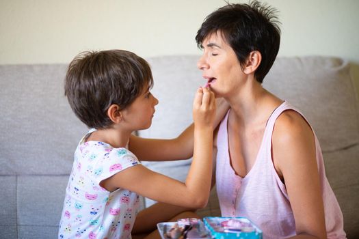 Mother and her little daughter doing make up for each other