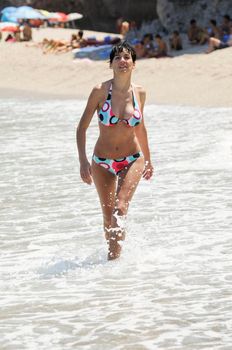 Woman with beautiful body in swimwear smiling in a tropical beach.