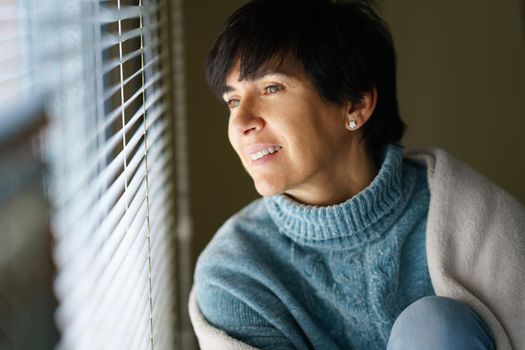 Happy middle-aged woman smiling while looking out the window.