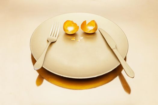 Cutlery and golden eggshell on plate placed on reflective table