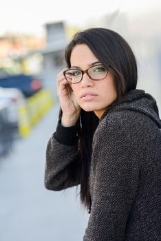 Young woman with green eyes and eyeglasses in urban background
