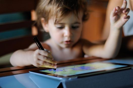 Little girl painting with a digital tablet at home.