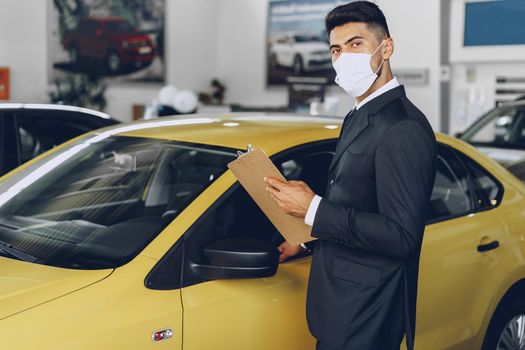 Man car dealer wearing protective medical mask on his working place