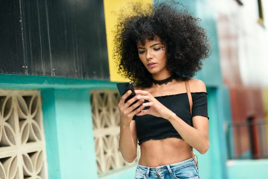 Black woman afro hair on the street holding a smartphone