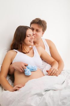 happy young pregnant woman with husband on bed
