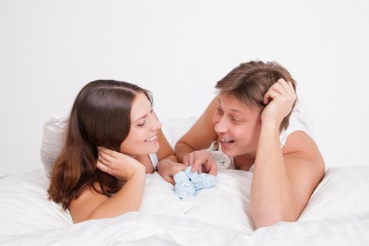 happy young pregnant woman with husband on bed