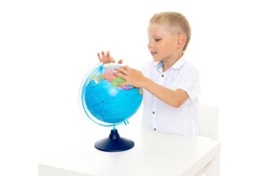 A little boy is studying geography on a globe.