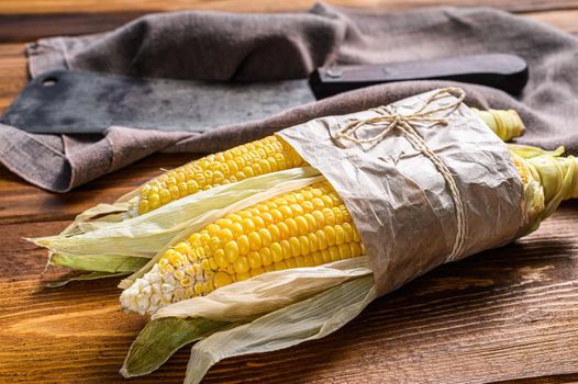 Fresh harvested corn cob on farmer market, local vegetables. Wooden background. Top view