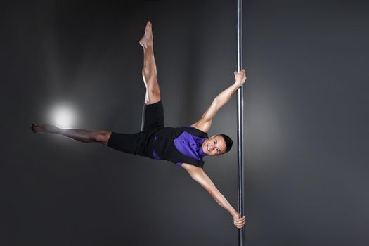 Pole dance man over black background with flashes