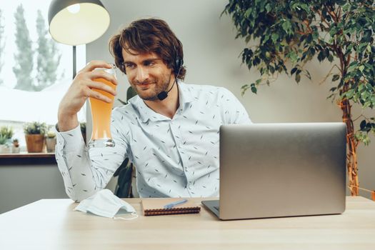 Bearded man using his laptop while drinking glass of beer