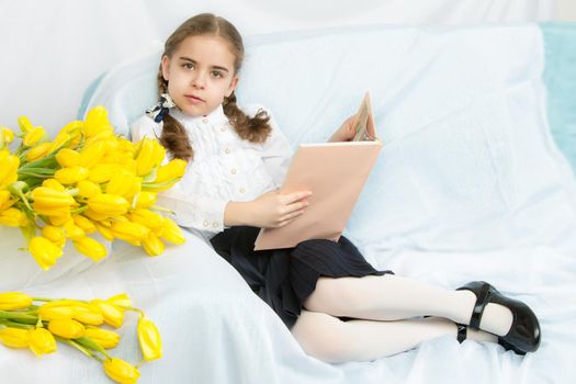 A diligent schoolgirl student with yellow tulips is sitting on t