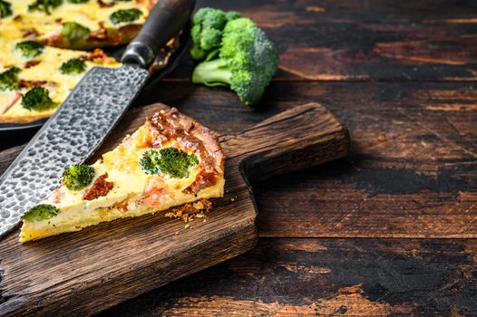 Quiche tart with smoked salmon, broccoli and spinach. Dark wooden background. Top view. Copy space