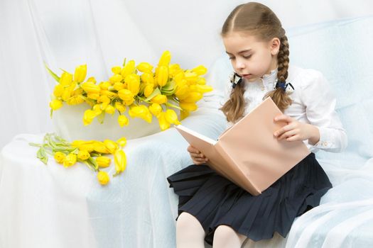 A diligent schoolgirl student with yellow tulips is sitting on t