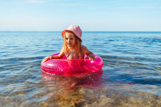 Happy little girl bathing in sea with pink circle