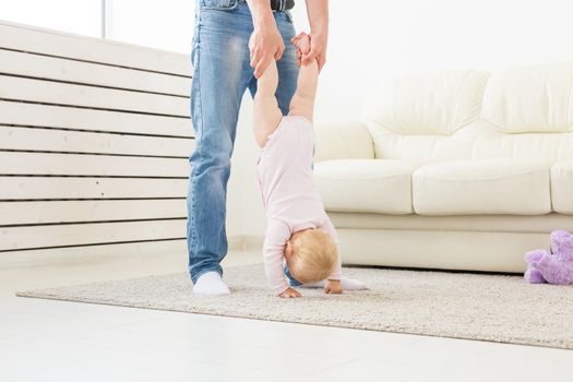 Fatherhood and family concept - Father and small toddler baby indoors at home, playing.