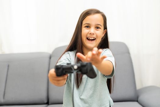 Girl with joystick. Excited little girl playing video game and smiling