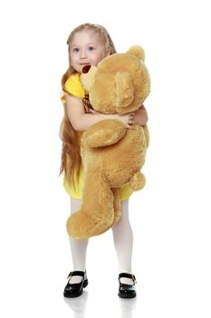 Girl hugs a big teddy bear.