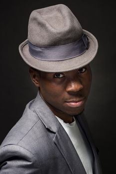 Close-up portrait of handsome black man with charming smile. Studio shot of well-dressed african guy wears hat and jacket.