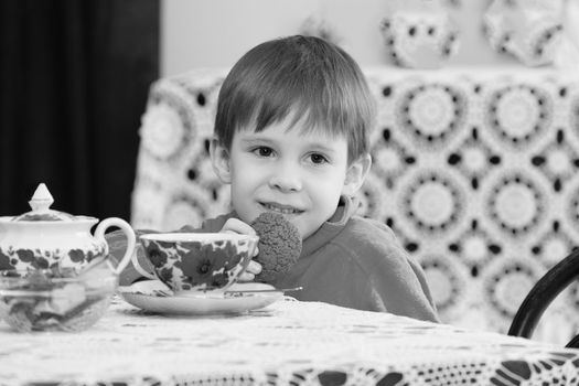 Little boy drinking tea at the table.