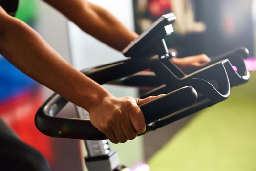Woman at a gym doing spinning or cyclo indoor with smart watch