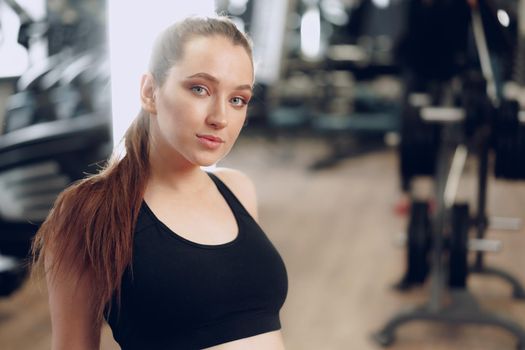 Brunette young woman sitting tired in a gym after workout