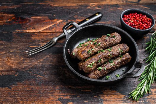 Grilled mince meat sausages in a pan. Dark wooden background. Top view. Copy space
